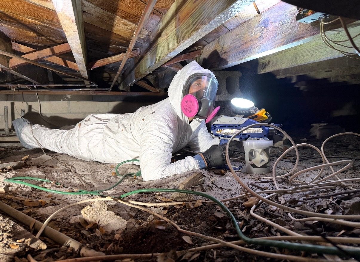 Pure Shield technician in protective gear inspecting the attic of a Coral Springs home