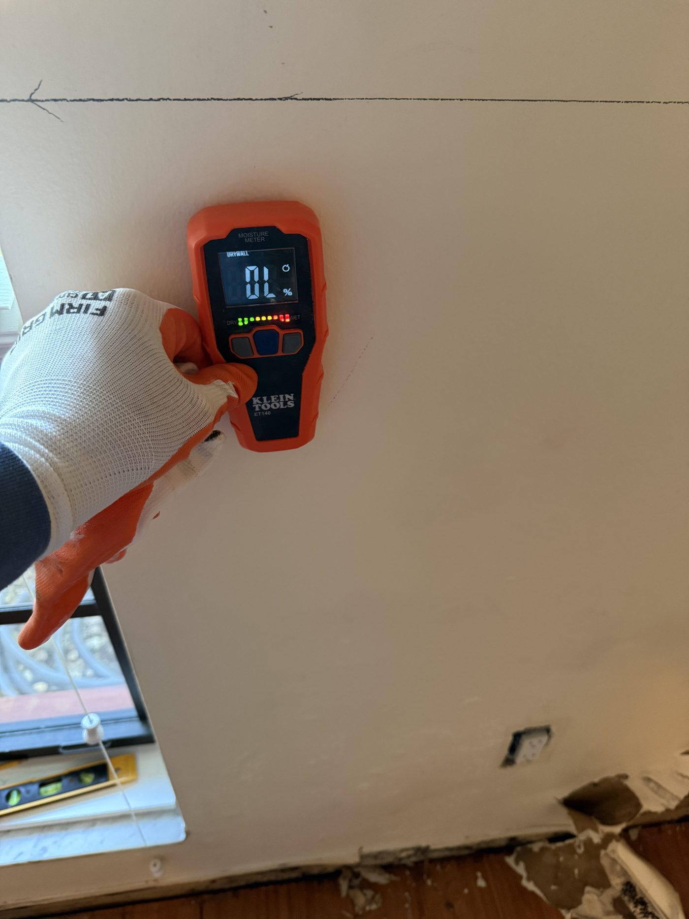 Moisture meter being held against a wall to take a reading during a water damage inspection