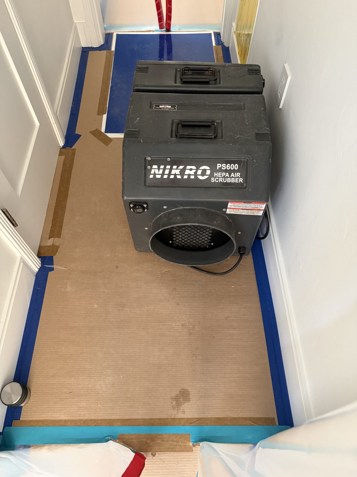HEPA air scrubber running on protected flooring during mold remediation in a Pompano Beach home